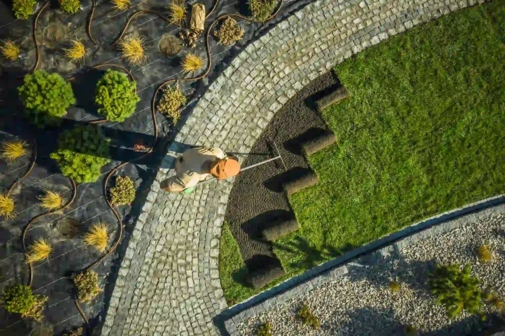 Overhead view of hardscape stone path beside green lawn and landscaped plants showing design contrast